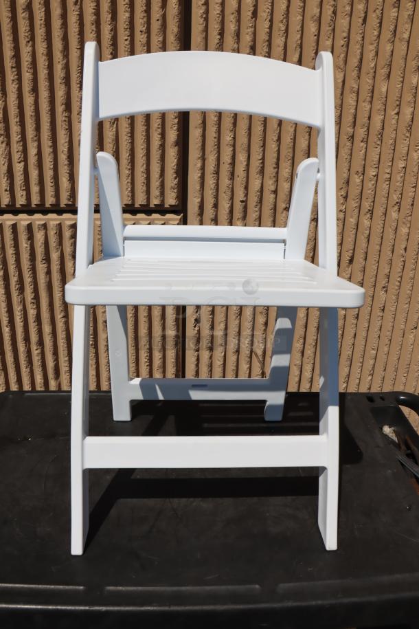 Lancaster Table & Seating white resin folding chair with slatted seat, model 427FCRSLTWHT, new condition, exposed.