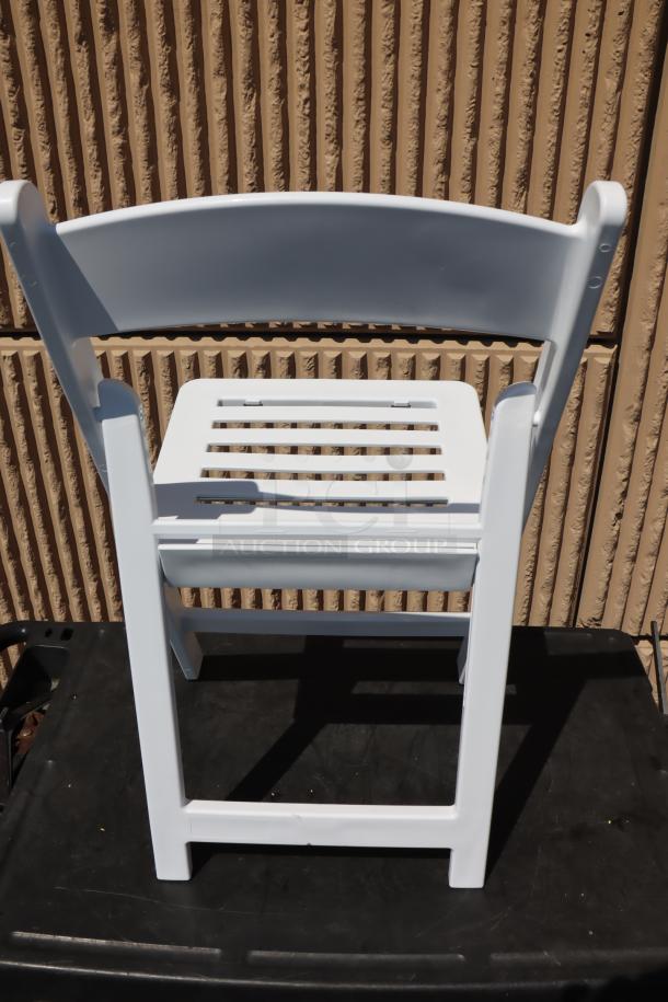 White resin folding chair by Lancaster Table & Seating, model 427FCRSLTWHT, with slatted seat, new condition, 16 available.