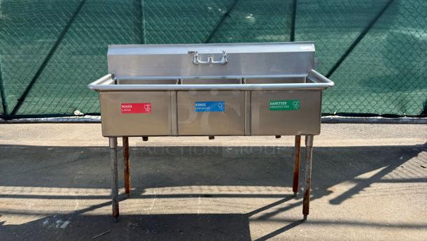 Stainless steel triple sink with labeled basins for wash, rinse, sanitize. Used condition, some rust on legs.