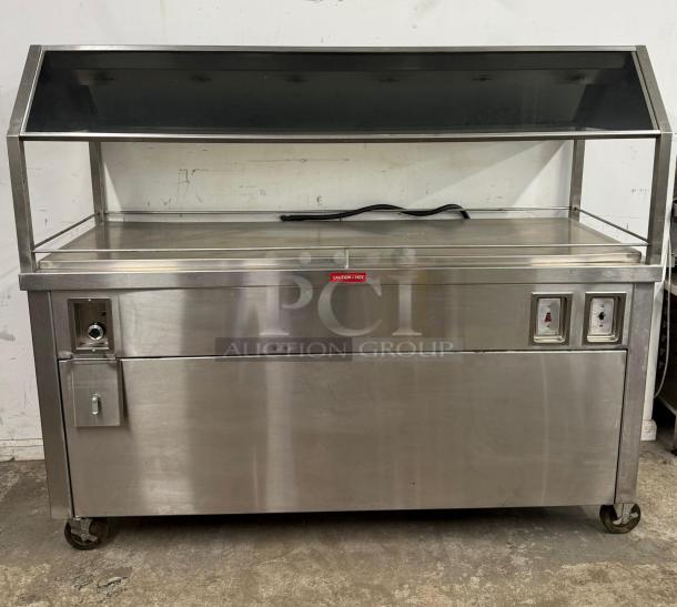 Stainless steel hot food merchandiser with glass display, control panel, and storage, on wheels. Good condition.