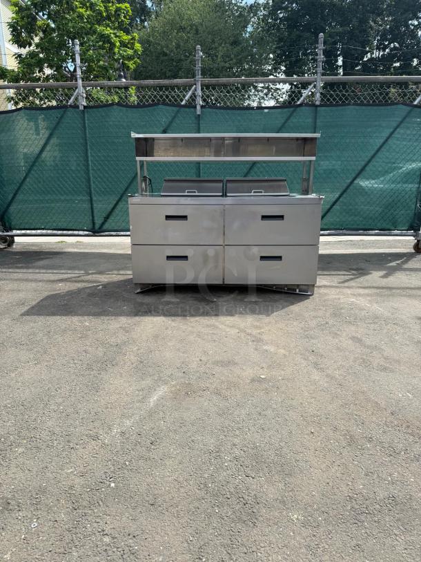 Delfield D4464NP 4-drawer refrigerated prep table with mega top and 5" casters, stainless steel finish, outdoors.