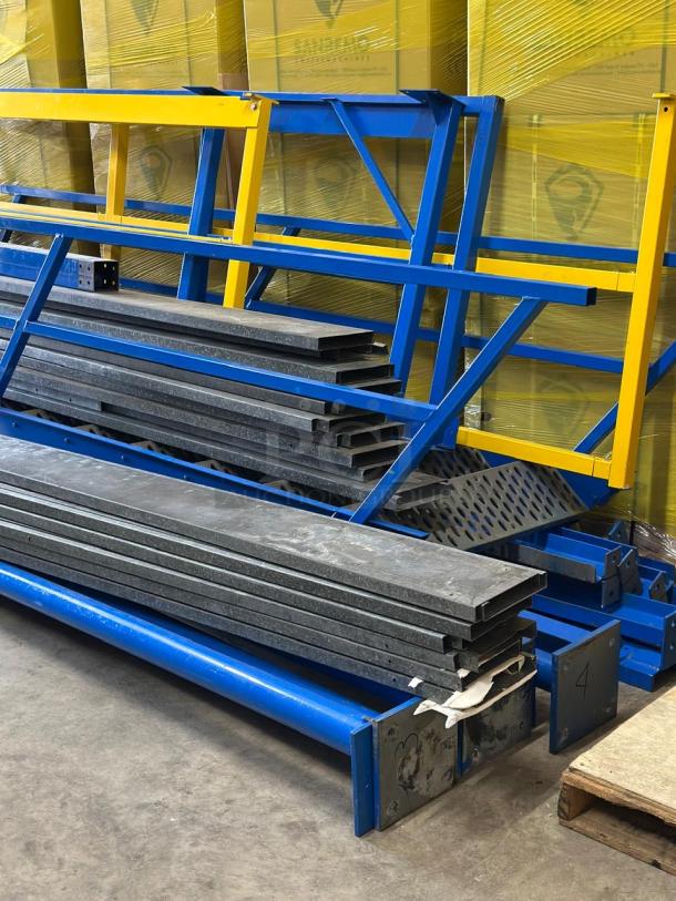 Disassembled warehouse mezzanine in used condition, featuring blue and yellow frames with metal planks. Ready for pickup.