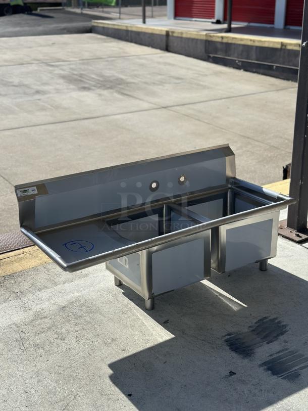 Brand new Regency 57" two-compartment stainless steel sink, 16 gauge, with left drainboard. Model 600S2171718L, scratch and dent condition.