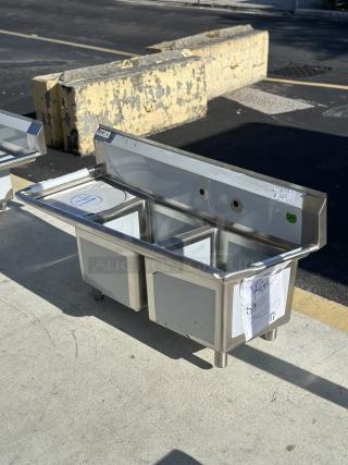 Brand new Regency 57" stainless steel dual-compartment sink, model 600S2171718L, with left drainboard; scratch and dent condition.
