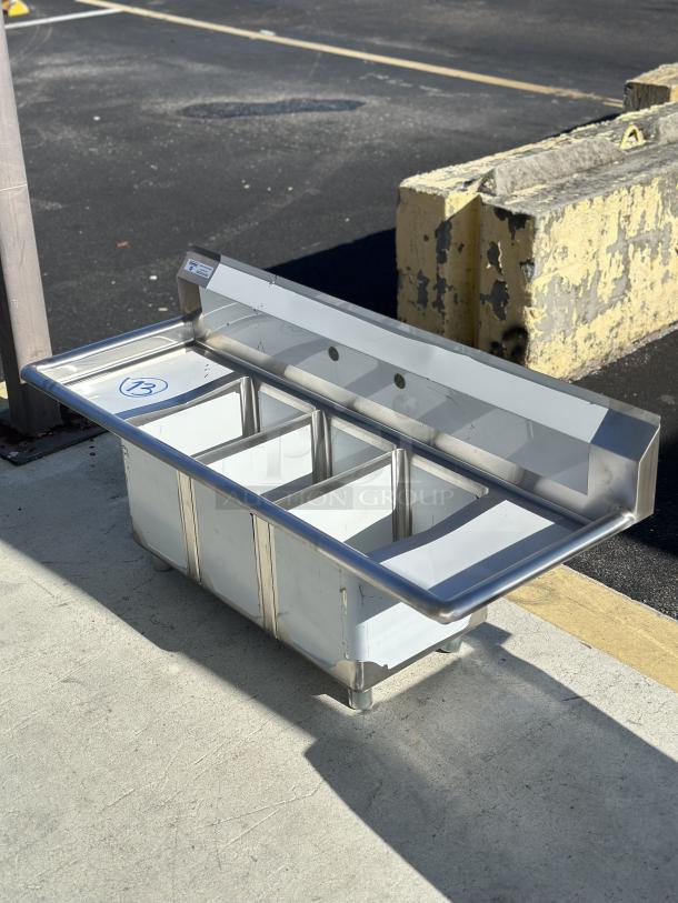 Steelton 54" stainless steel 3-compartment sink, model 522CS31014LR. Features two drainboards, 10"x14"x12" bowls, new condition.