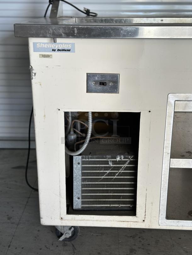 Used Shelleyglas by Delfield serving station with undershelf. Visible signs of wear. Brand label and power switch present.