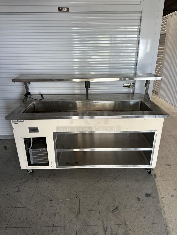 USED Shelleyglas by Delfield serving station with undershelf. Features stainless steel top and wheels. Tag reads "Shelleyglas."