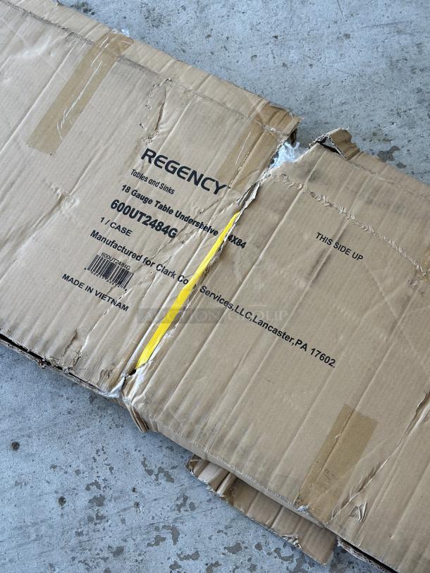 Regency 18-gauge steel shelf for 24"x84" tables, model 600UT2484G, in original box with visible wear. Made in Vietnam.