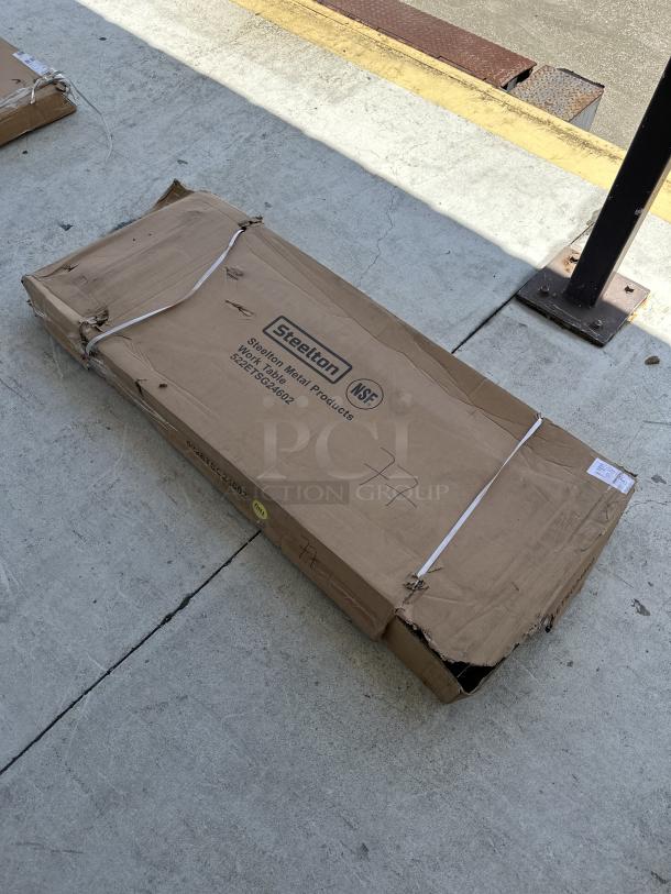 Sealed box of Steelton 24"x60" stainless steel work table, model 522ETSG24602, with visible box damage and branding.