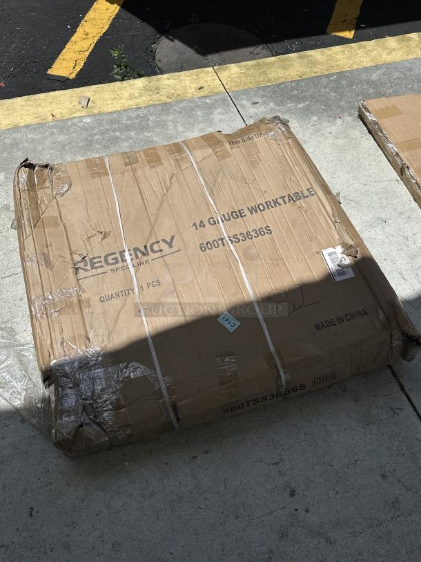 Regency Spec Line commercial work table, model 600TSS3636S, new with scratches, in original packaging with visible marks.
