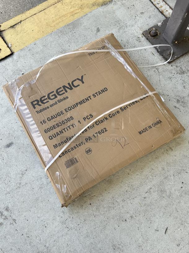 New Regency 600ES3030S 30" x 30" stainless steel equipment stand in original packaging, model label visible.