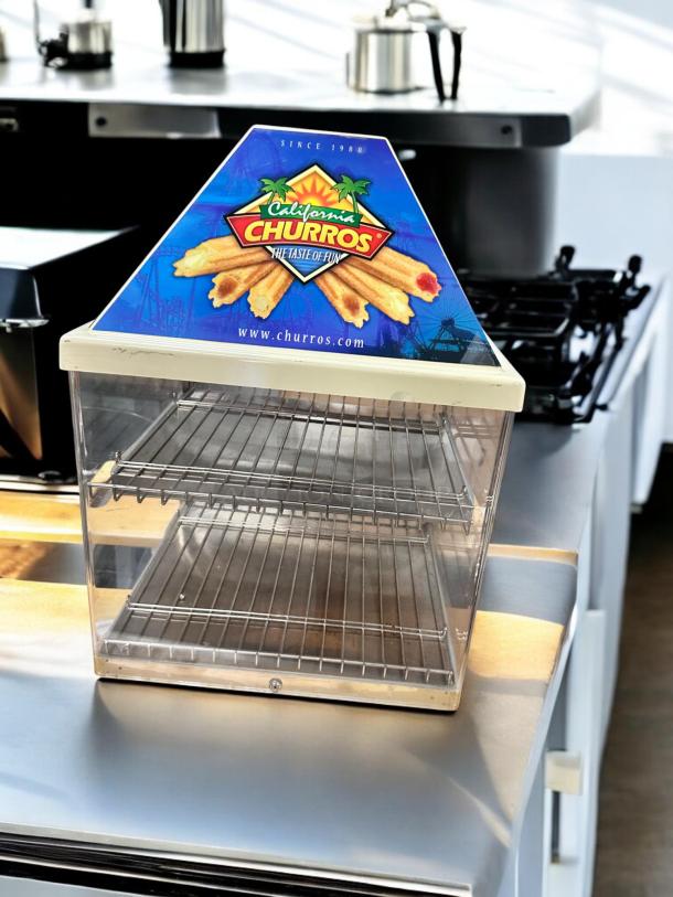 Wisco 680-1 food warmer, excellent condition, 120V, transparent display cabinet, wire shelves, "California Churros" sign.