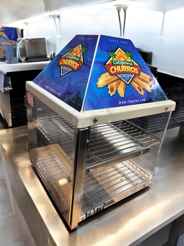 Wisco 680-1 food warmer/display cabinet, excellent condition, 120V. Features glass panels, metal racks, California Churros signage.
