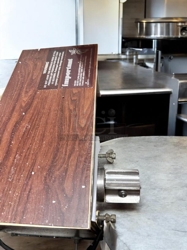 Brand new Norwalk Model 235 hydraulic press juicer, 110V, in original packaging. Features wood grain finish with labeled warnings.