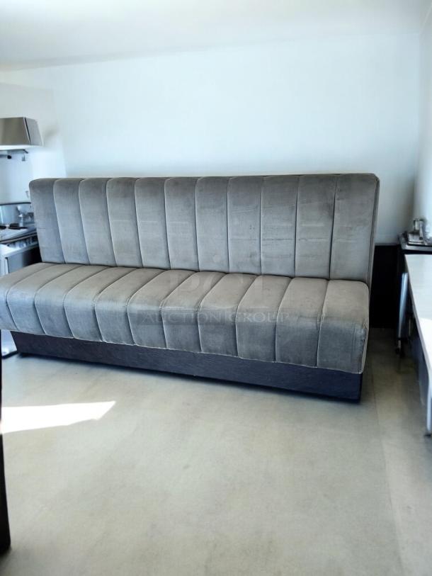 Gray upholstered booth bench, 82" wide, excellent condition, vertical stitching. Ideal for restaurant use.
