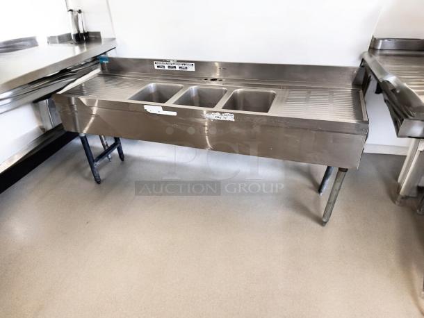 Three-compartment stainless steel bar sink, 72"x24"x35", in excellent condition, with dual drainboards and visible labels.