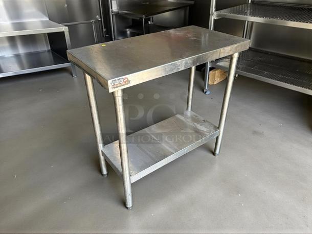 Stainless steel worktop table in great condition, features sturdy legs and lower shelf. Visible label indicates quality.