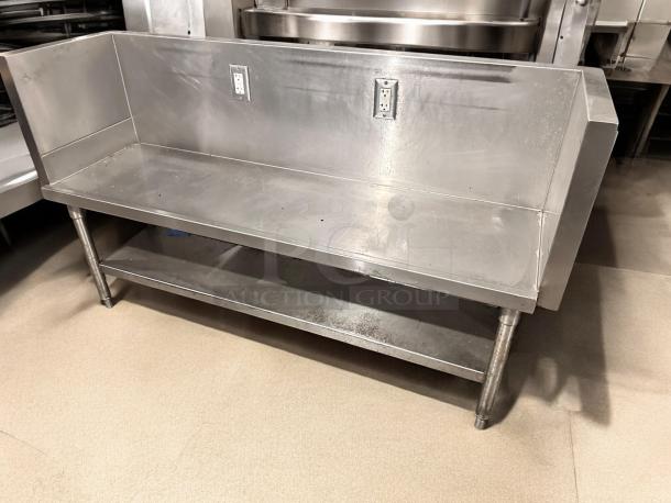Stainless steel commercial work table with undershelf, 65"x24"x40", features two electrical outlets, excellent condition.