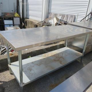 Stainless steel table, 72x30x34 inches, with under shelf. Used condition, visible scratches and wear. Ideal for kitchen or workshop.