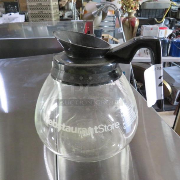 Glass coffee pot with black handle and lid, labeled "Webstaurant Store." Used condition, no visible chips or cracks.