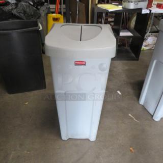 Rubbermaid 23-gallon trash can with flip lid, gray, prominent Rubbermaid logo, good condition, ideal for commercial use.