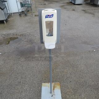 Purell hand sanitizer station on stand, used condition, visible rust on base, suitable for public or workplace use.