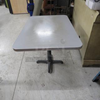 Gray laminate table top on a dual pedestal base, measuring 60x30x30 inches. Good condition, some surface wear.