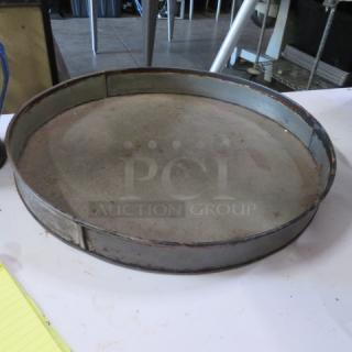 18.5-inch commercial bake pan, round, well-used condition, metal with slight rust, industrial kitchen setting.