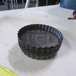Wilton 4x1 inch mini tart/quiche pans, stack of 6, black non-stick, fluted edges, used condition with visible brand marking.