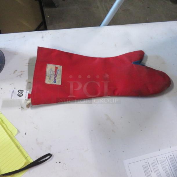 Red Tucker Burn Guard Glove, single, gently used, with safety label visible. Auction item tagged "68".