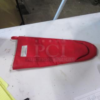 Red Tucker Burn Guard Glove on table, featuring a protective label indicating heat resistance. Good condition.