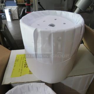 Box of 7-inch Royal pleated chef hats, white, stacked on boxes, showing pleated design and ventilation holes.