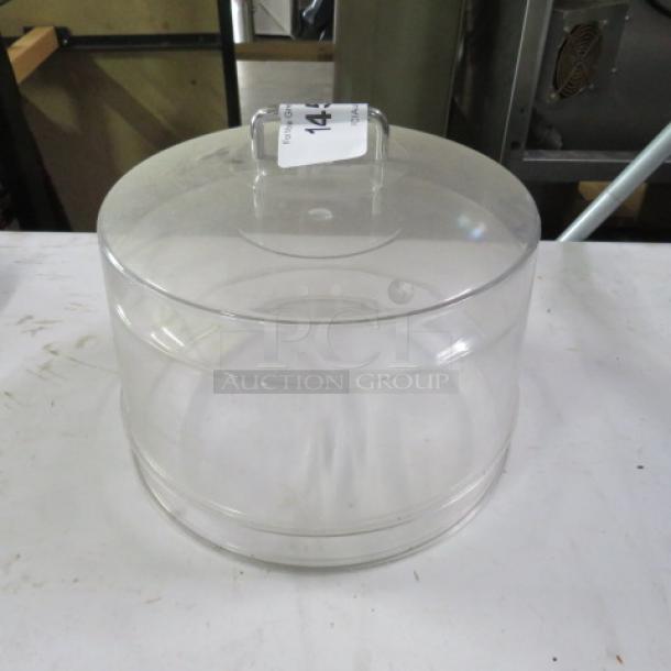 Clear 12-inch dome cake lid, sturdy, with handle and marked "2XBID" tag. Suitable for cake presentation and storage.
