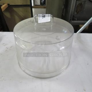 Clear 12-inch dome cake lid, sturdy, with handle and marked "2XBID" tag. Suitable for cake presentation and storage.