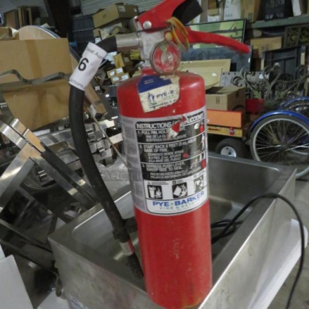 Red ABC fire extinguisher, Pye-Barker brand, attached hose, visible instructions, moderate wear, auction label number 6.