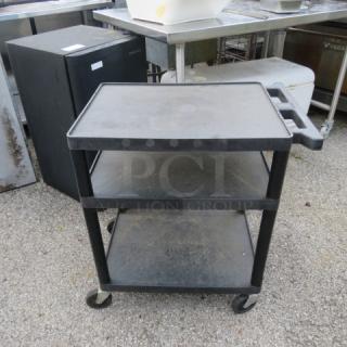 Three-shelf poly cart on casters, 28x18x30 inches, black, used condition, handle and wheels for mobility.