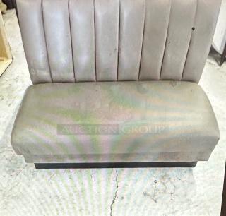 Single-sided gray cushioned booth, 48x27x45, shows wear with stains and scuffs. Ribbed backrest, solid base, commercial use.