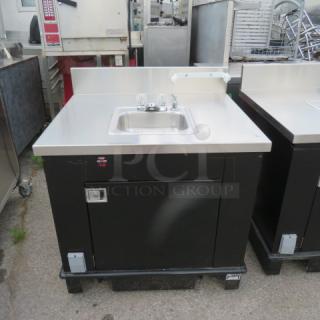 Corsair stainless steel portable sink with faucet, paper towel holder, 5-gallon fresh water tank, 7-gallon waste tank, on casters.