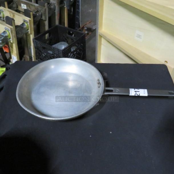 10.5-inch sauté pan with metal handle on black surface, showing some visible wear.