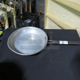 10.5-inch sauté pan with metal handle on black surface, showing some visible wear.