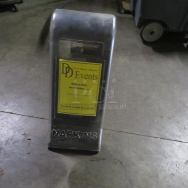 One Tork Xpressnap napkin dispenser, translucent with event label, used condition, suitable for high-traffic areas.