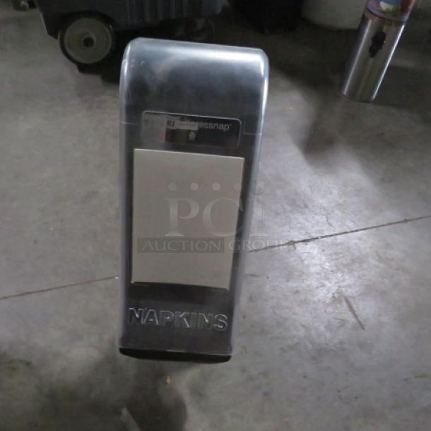 Tork Xpressnap napkin dispenser, tabletop model, transparent casing, visible "NAPKINS" label, lightly used condition.