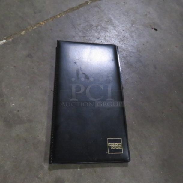 Lot of 5 black guest check holders, leather appearance, American Express logo, used condition, slight scuffs visible.