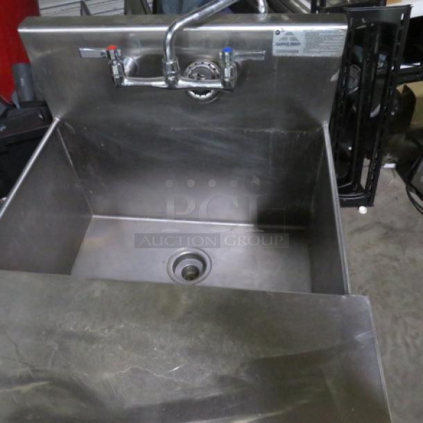 Stainless steel sink with faucet and cover, 26.5x25x41 inches, good condition, visible control tags for hot and cold water.