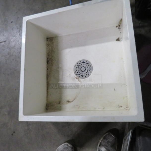 One white mop sink, 24x24x10 inches, showing some dirt and wear. Features central drain. Good for utility cleaning tasks.