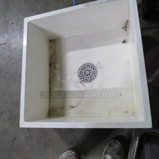 One white mop sink, 24x24x10 inches, showing some dirt and wear. Features central drain. Good for utility cleaning tasks.