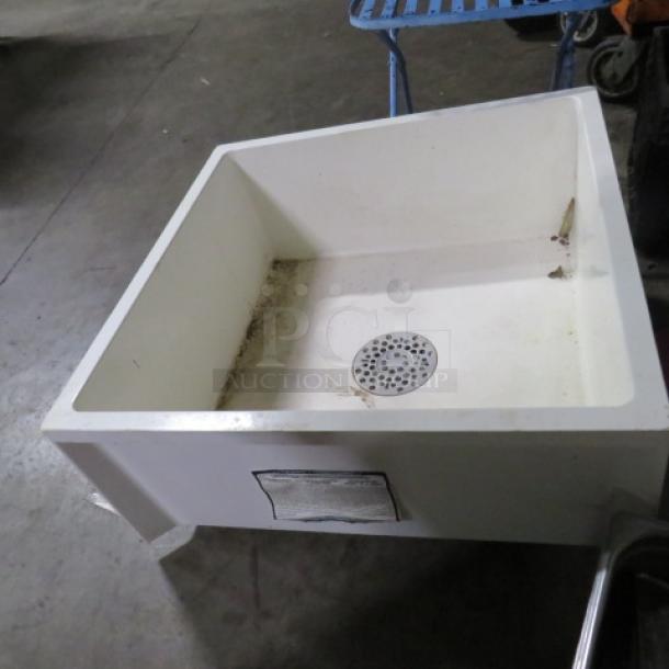 White mop sink, dimensions 24x24x10 inches, with visible drain. Slight wear present. Used for cleaning purposes.