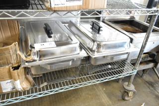 Two brand new stainless steel chafing dishes, minor scratches and dents, with black handles, placed on a metal rack.