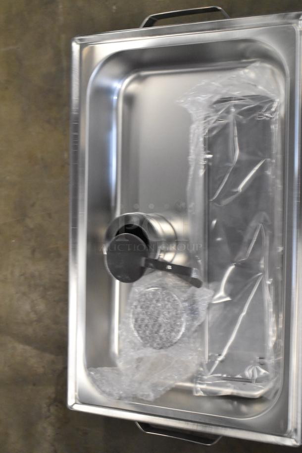 Brand new stainless steel chafer, with minor scratches and dents, visible plastic wrapping and handle on lid.