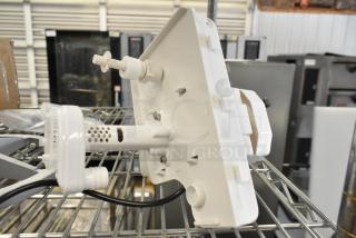 Brand new pump with minor scratches and dents, white plastic, mounted on metal rack, visible vents, and connecting ports.